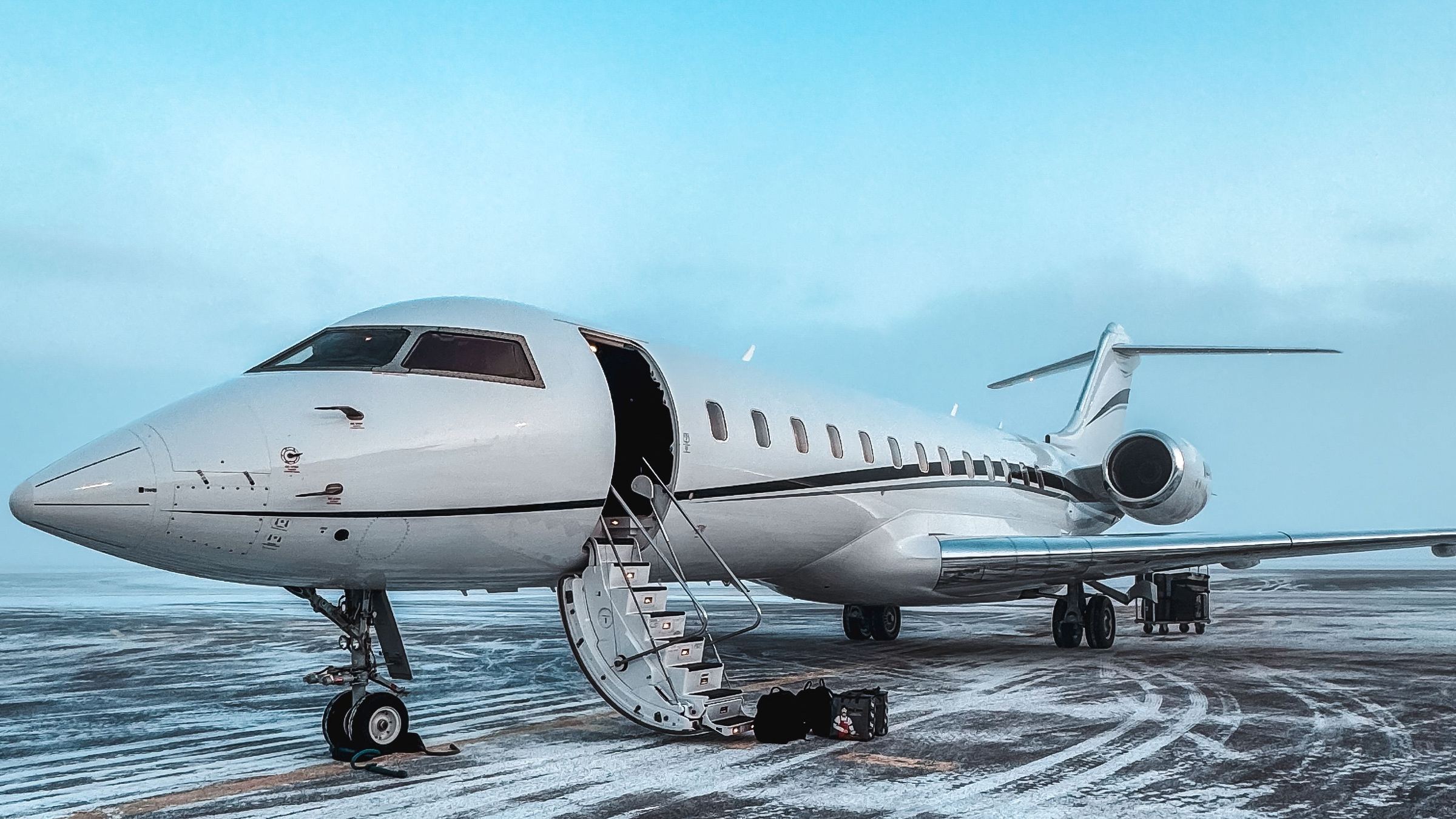 A business jet on a snowy apron with its airstair down.