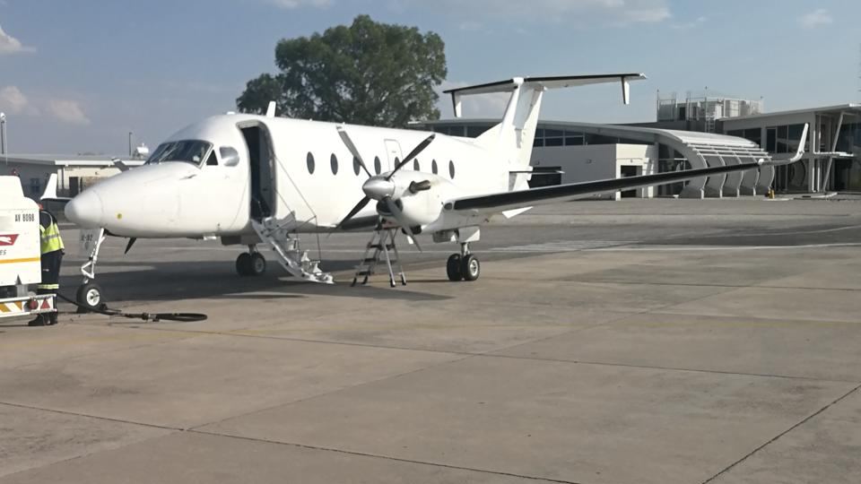 A white Beechcraft 1900D with its airstair down, being refuelled on a ramp.