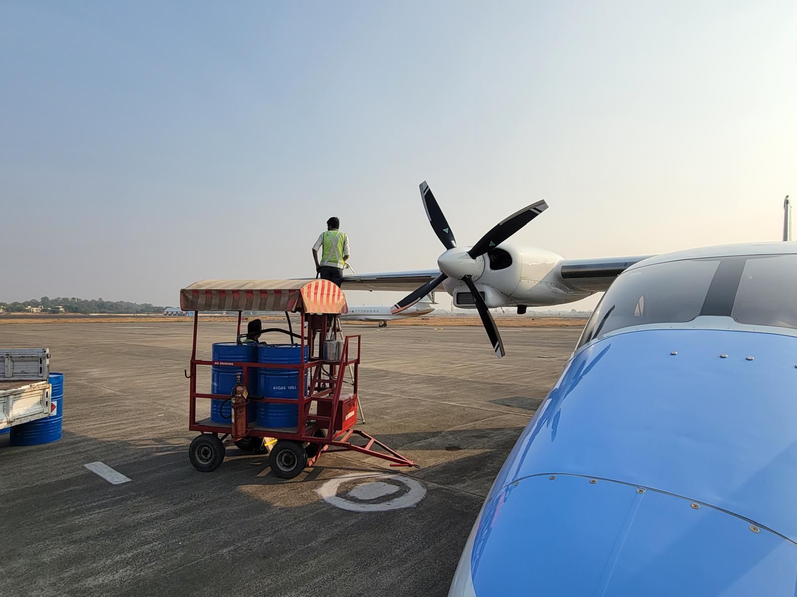 A Tecnam P2012 being refuelled by hand from fuel drums.