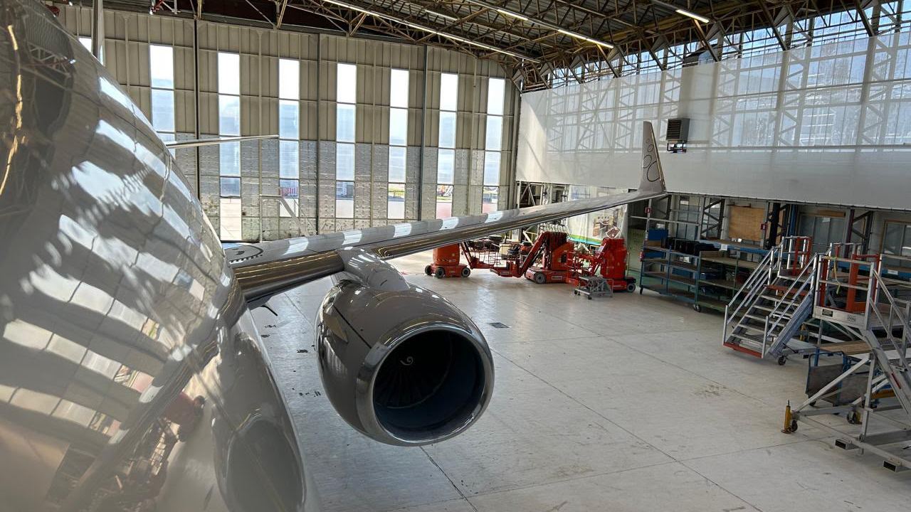 The wing, engine and winglet of a Boeing jet in a hangar.