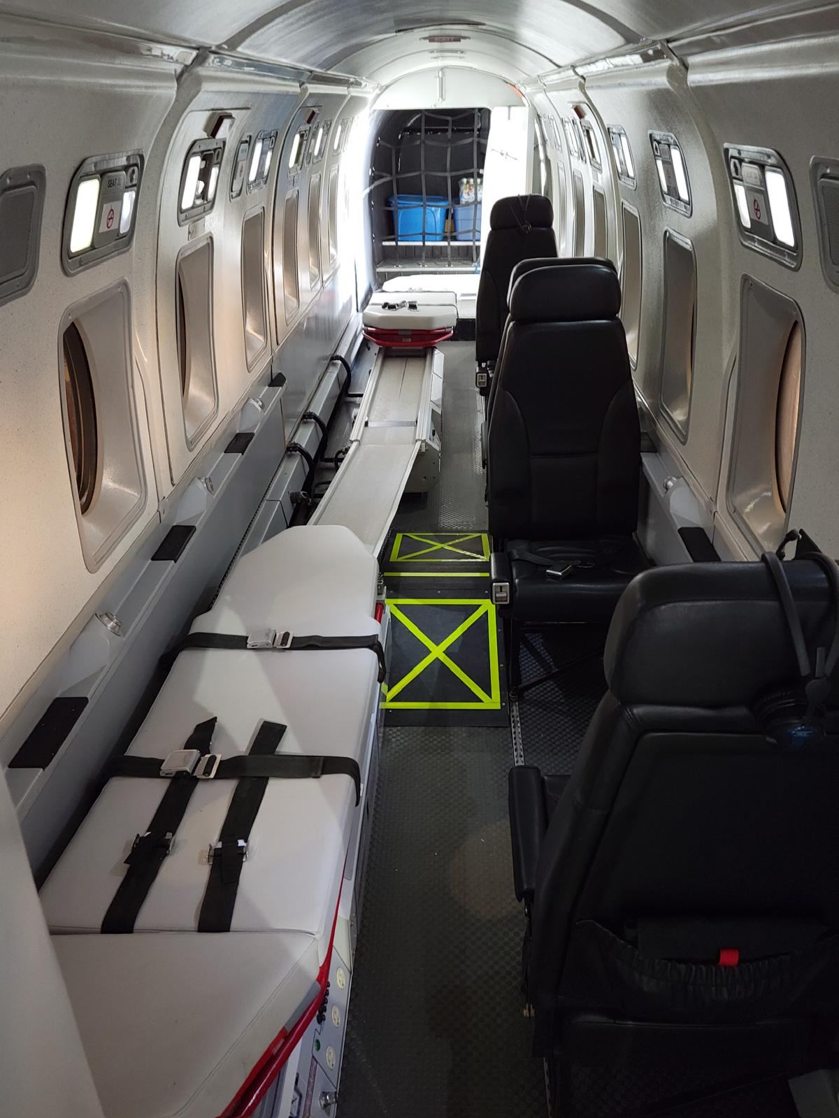 A stretcher with a medical console, the floor rail running forward to a second stretcher position.