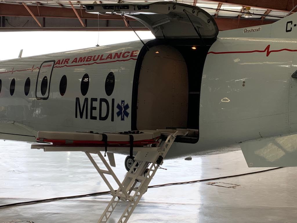 A loaded stretcher on a powered loader at the open rear door of an air ambulance.