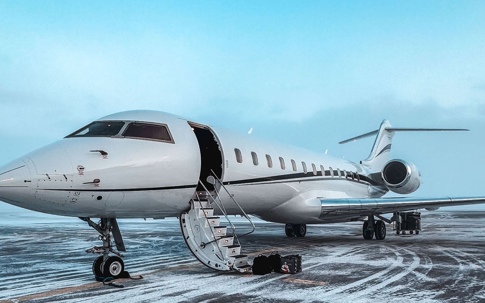 A business jet on a snowy apron with its airstair down.