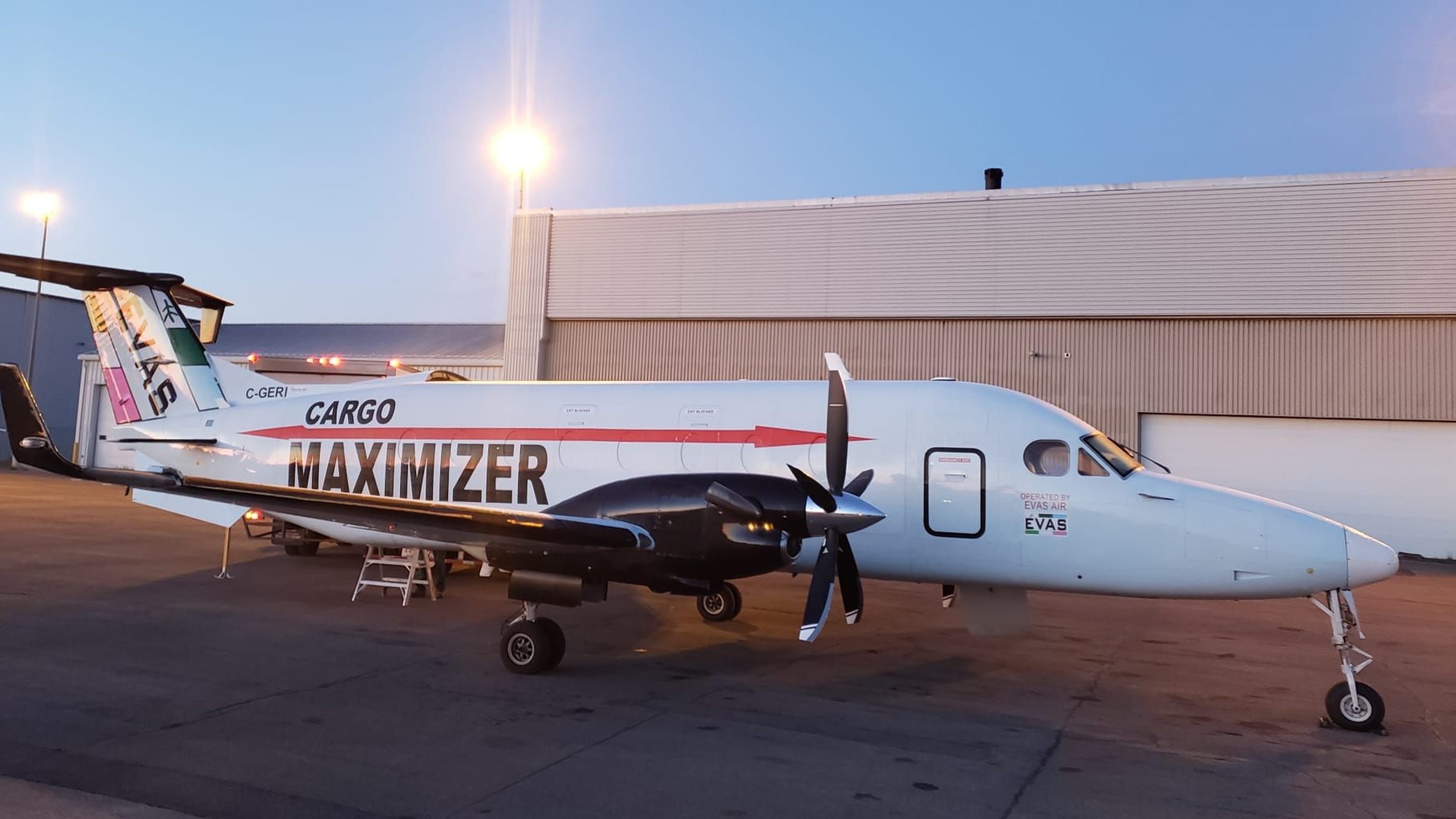 A Beechcraft 1900D freighter with Cargo Maximizer and EVAS markings parked on a ramp at dusk